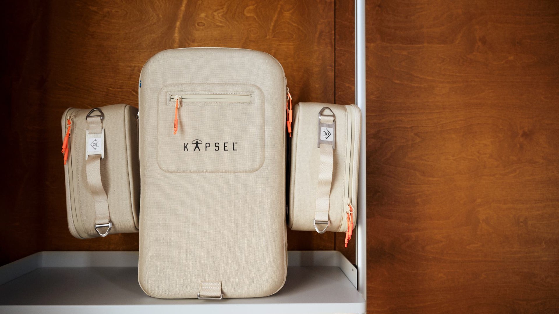 Beige emergency preparedness bag with 'KAPSEL' branding on a wooden shelf.