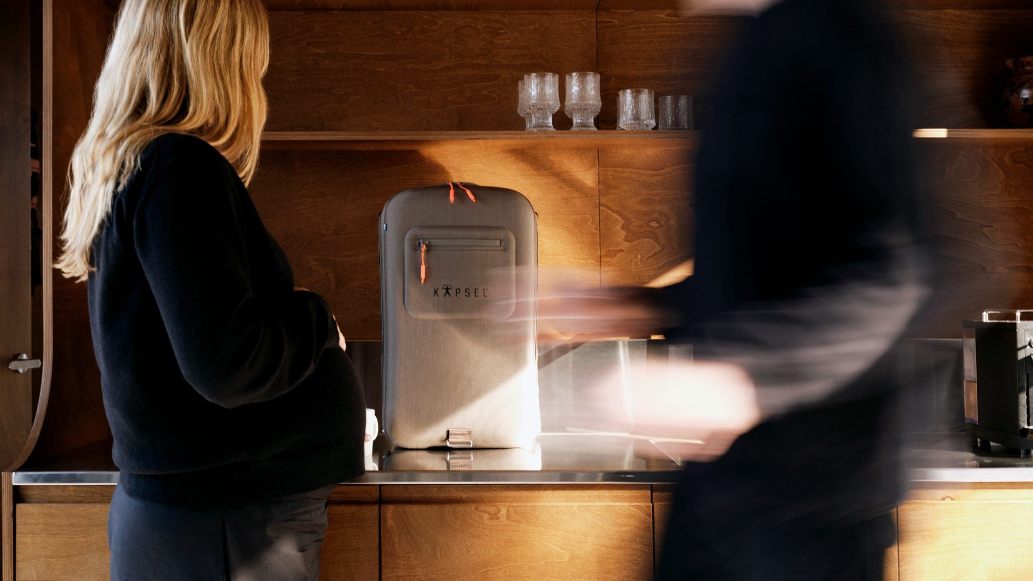 Two people in a kitchen with a coffee machine on the counter.